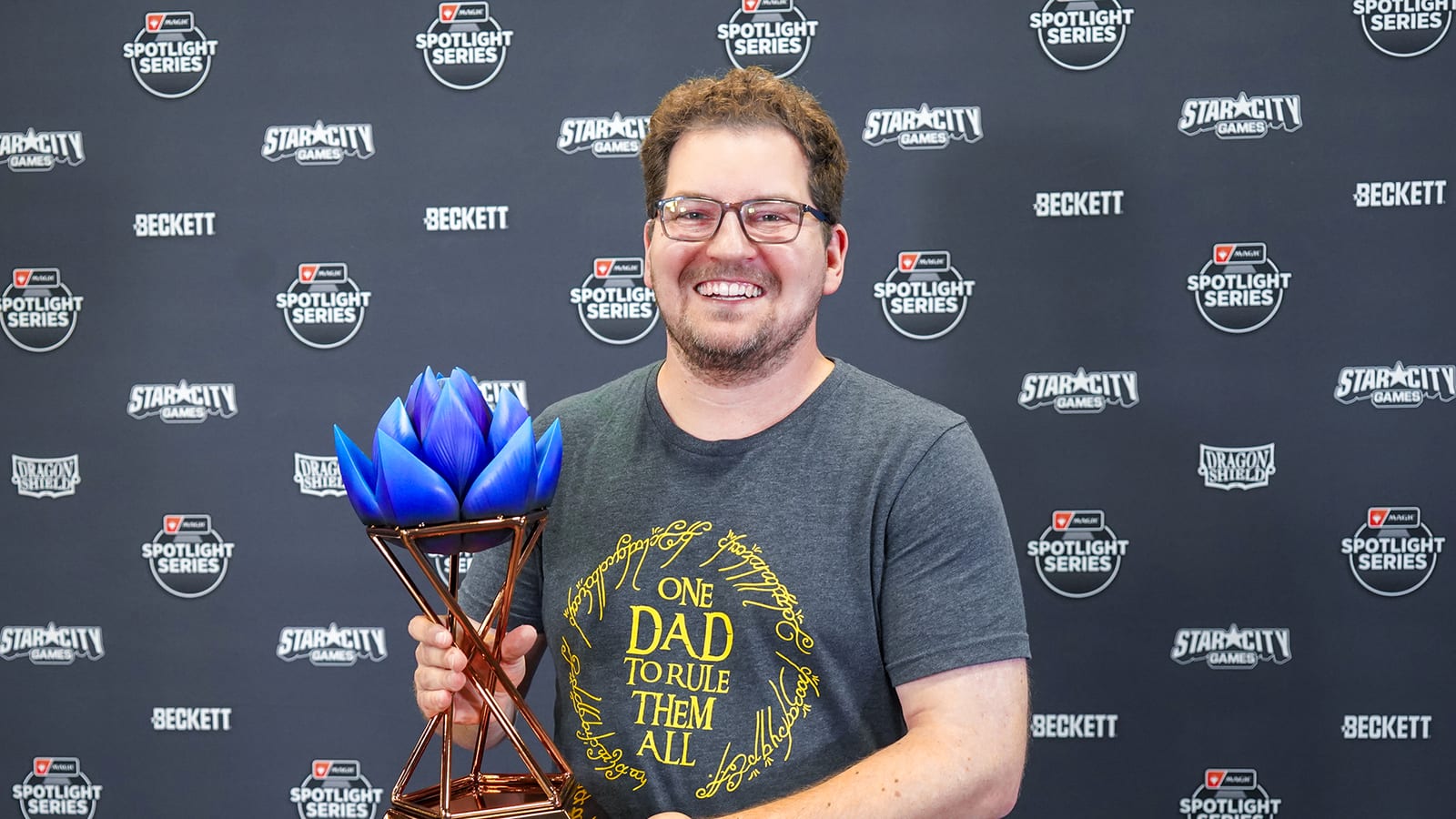 Roy Varney smiling and holding the blue lotus trophy after winning Magic Spotlight: The Hobbit in Dallas